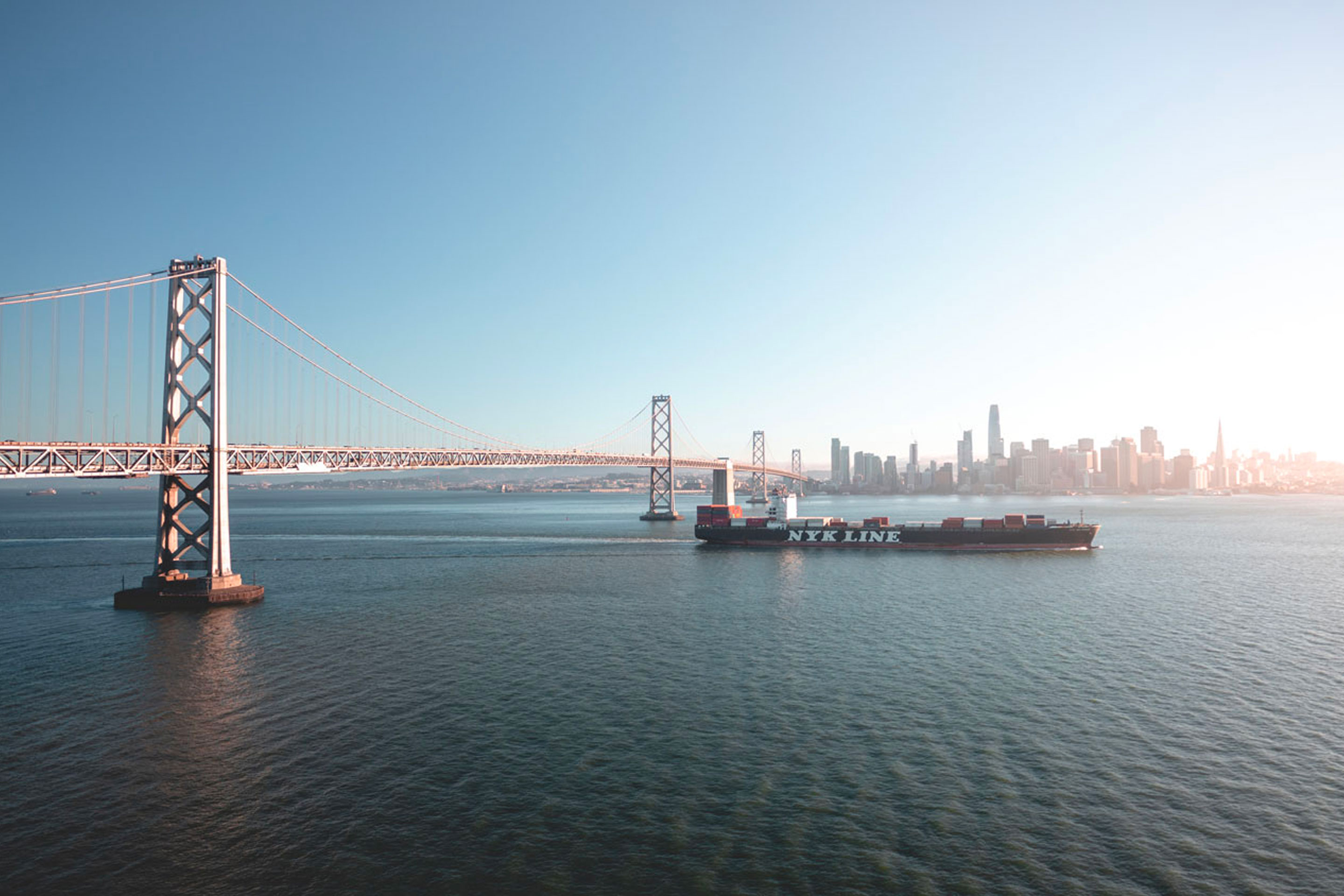 A ship at sea with a bridge in the background