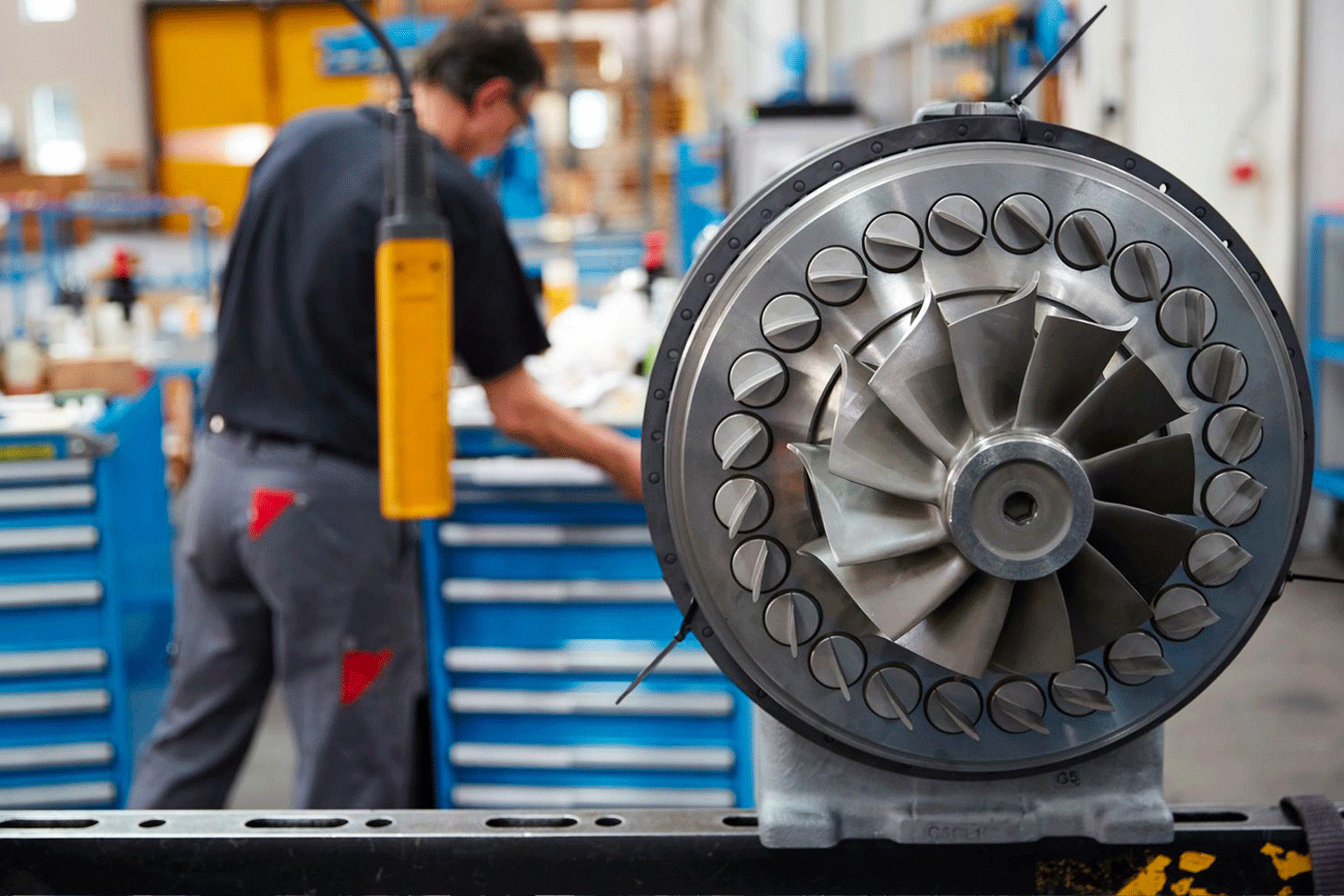 A turbocharger turbine with an engineer in the background